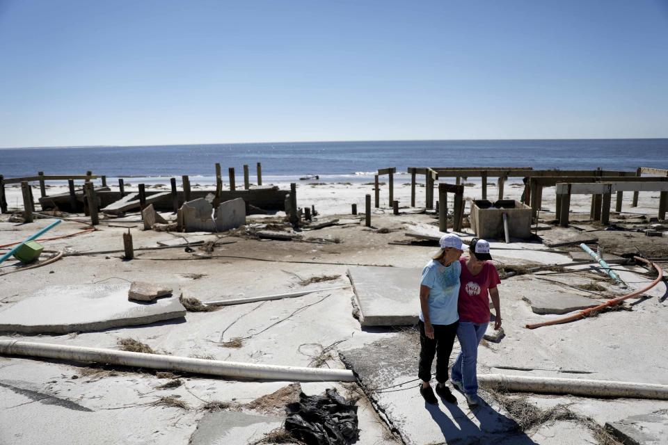 FILE - In this Oct. 12, 2018, file photo, Joy Hutchinson, left, is comforted by her daughter Jessica Hutchinson, as she returns to find her home swept away from hurricane Michael in Mexico Beach, Fla. The tropical weather that turned into monster Hurricane Michael began as a relatively humble storm before rapidly blossoming into the most powerful cyclone ever to hit the Florida Panhandle, causing wrenching scenes of widespread destruction.(AP Photo/David Goldman, File)