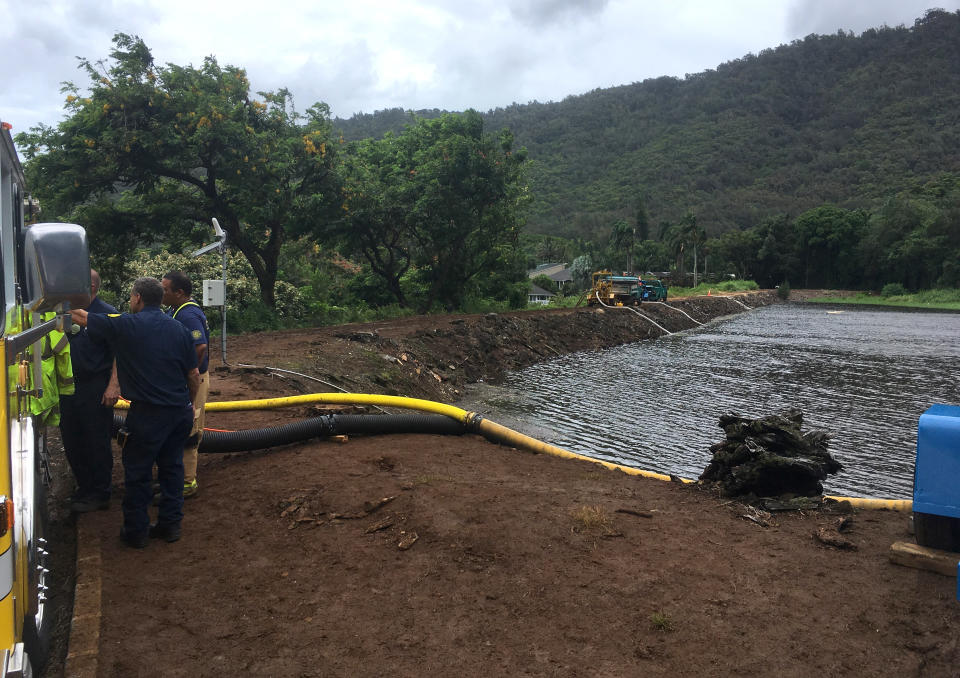 Officials pump water from a reservoir where a dam came close to overflowing in Honolulu on Thursday, Sept. 13, 2018. Honolulu officials say they may need to evacuate 10,000 people from a residential neighborhood if water in the reservoir continues to rise after heavy rains from a tropical storm. (AP Photo/Caleb Jones)