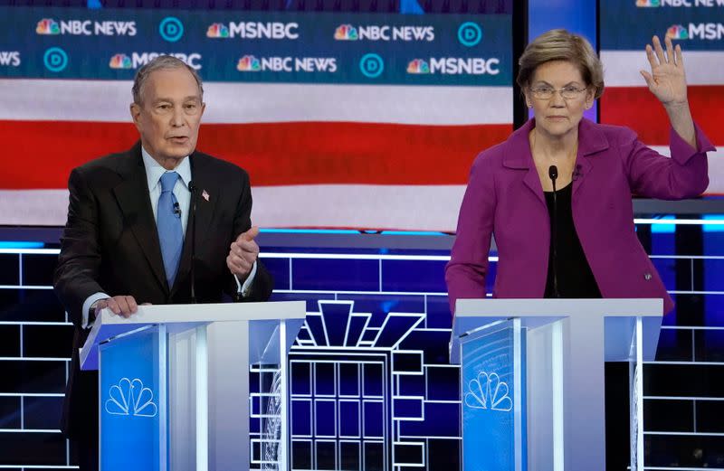 Senator Elizabeth Warren raises her hand to speak as former New York City Mayor Mike Bloomberg answers a question at the ninth Democratic 2020 U.S. Presidential candidates debate at the Paris Theater in Las Vegas