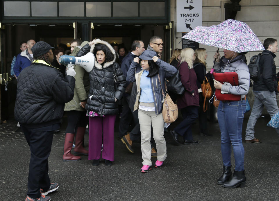 A transit official directs crowds with a megaphone at Hoboken Terminal in Hoboken, N.J., Tuesday, April 4, 2017. A minor derailment on Monday at Penn Station involving a New Jersey Transit train and other rail issues are causing major problems for New York City metro area commuters. (AP Photo/Seth Wenig)