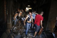 Protesters walk in an damaged building during clashes with police as part of a protest against the political elites and the government after this week's deadly explosion at Beirut port which devastated large parts of the capital in Beirut, Lebanon, Saturday, Aug. 8, 2020. (AP Photo/Thibault Camus)