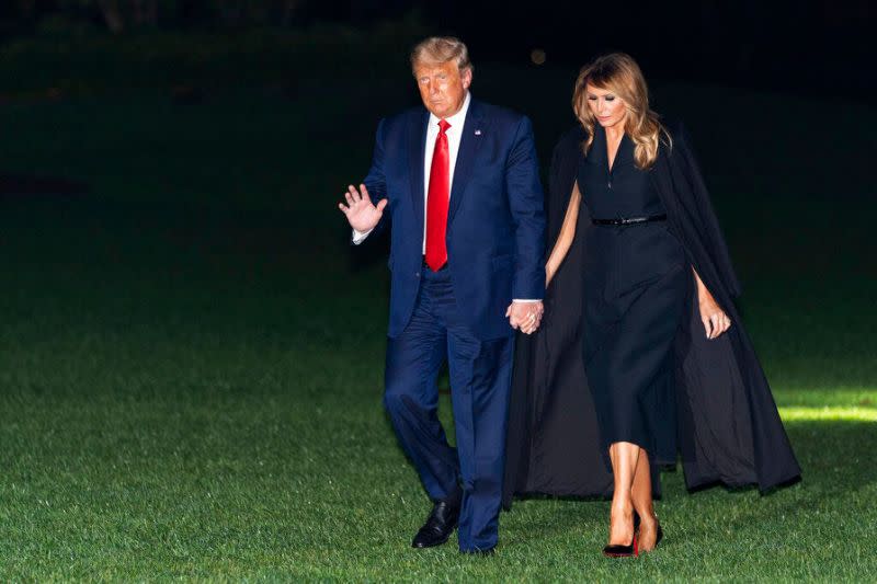 El presidente Donald Trump, acompañado por la primera dama Melania Trump, saludando mientras camina desde el Marine One en el jardín sur de la Casa Blanca, temprano el 23 de octubre de 2020. Trump regresaba de un debate en Nashville, Tennessee.