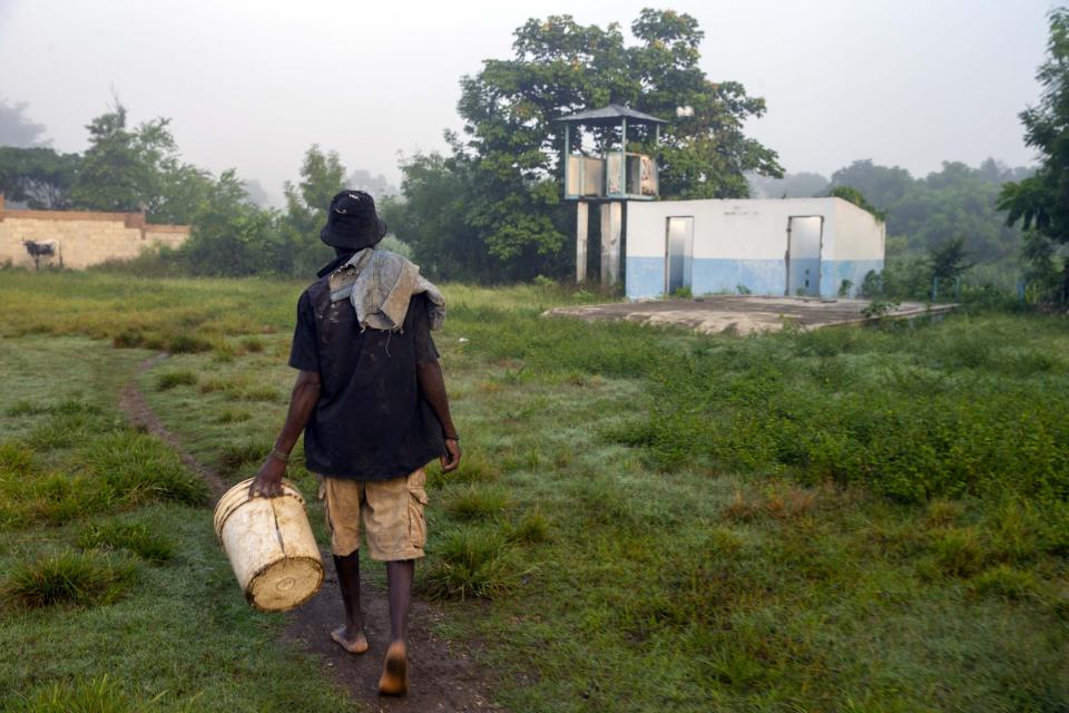 Lukcner Josapha, 43, walks through the former UN base to the Meille River to collect rocks he'll use to build his home outside the base in Mirebalais, Haiti, Monday, Oct. 19, 2020. Ten years after a cholera epidemic swept through Haiti and killed thousands, families of victims still struggle financially and await compensation from the United Nations as many continue to drink from and bathe in a river that became ground zero for the waterborne disease. (AP Photo/Dieu Nalio Chery)