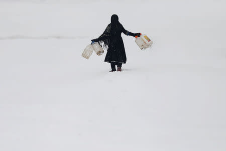 An Afghan girl carries empty water containers during a snowfall in Kabul, Afghanistan February 5, 2017. REUTERS/Mohammad Ismail