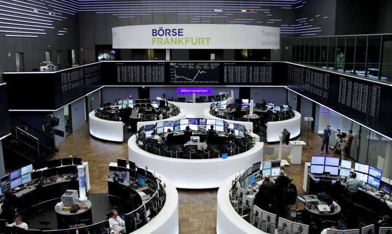 Traders work at their desks in front of the German share price index DAX board in Frankfurt