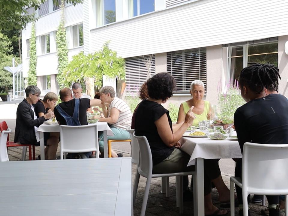 People sitting at two separate tables eating lunch.