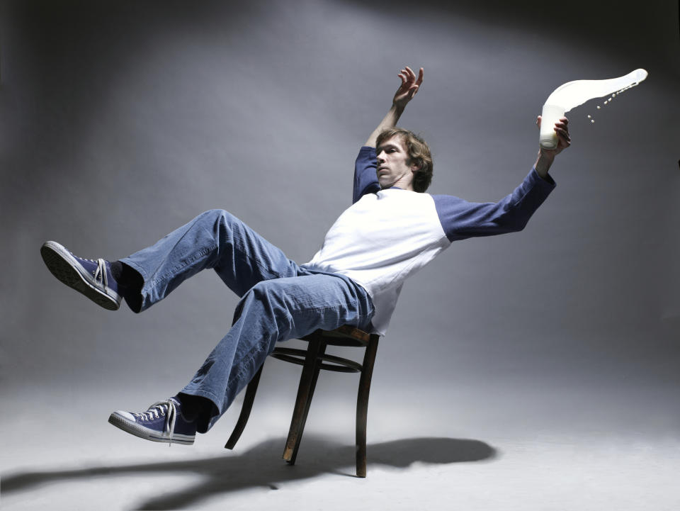 Person mid-fall from a chair with milk spilling from a glass