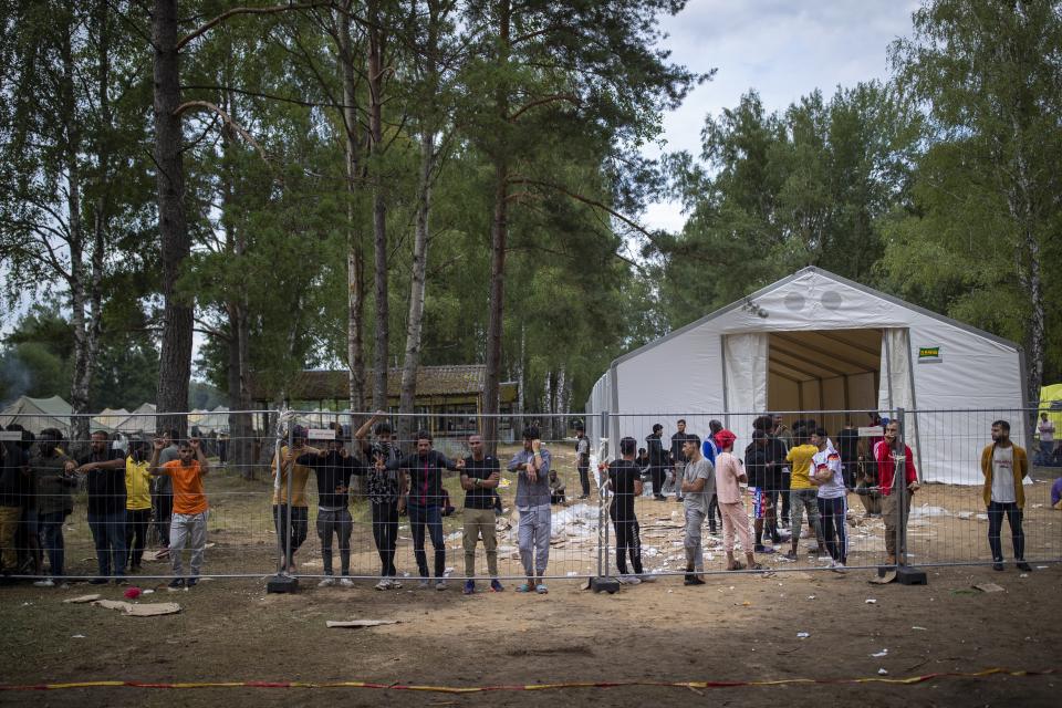 Migrants stand by the fence at the newly built refugee camp in the Rudninkai military training ground, some 38km (23,6 miles) south from Vilnius, Lithuania, Wednesday, Aug. 4, 2021. The Red Cross warned Wednesday that Lithuania's decision to turn away immigrants attempting to cross in from neighboring Belarus does not comply with international law. Lithuania, a member of the European Union, has faced a surge of mostly Iraqi migrants in the past few months. Some 4,090 migrants, most of them from Iraq, have crossed this year from Belarus into Lithuania. (AP Photo/Mindaugas Kulbis)