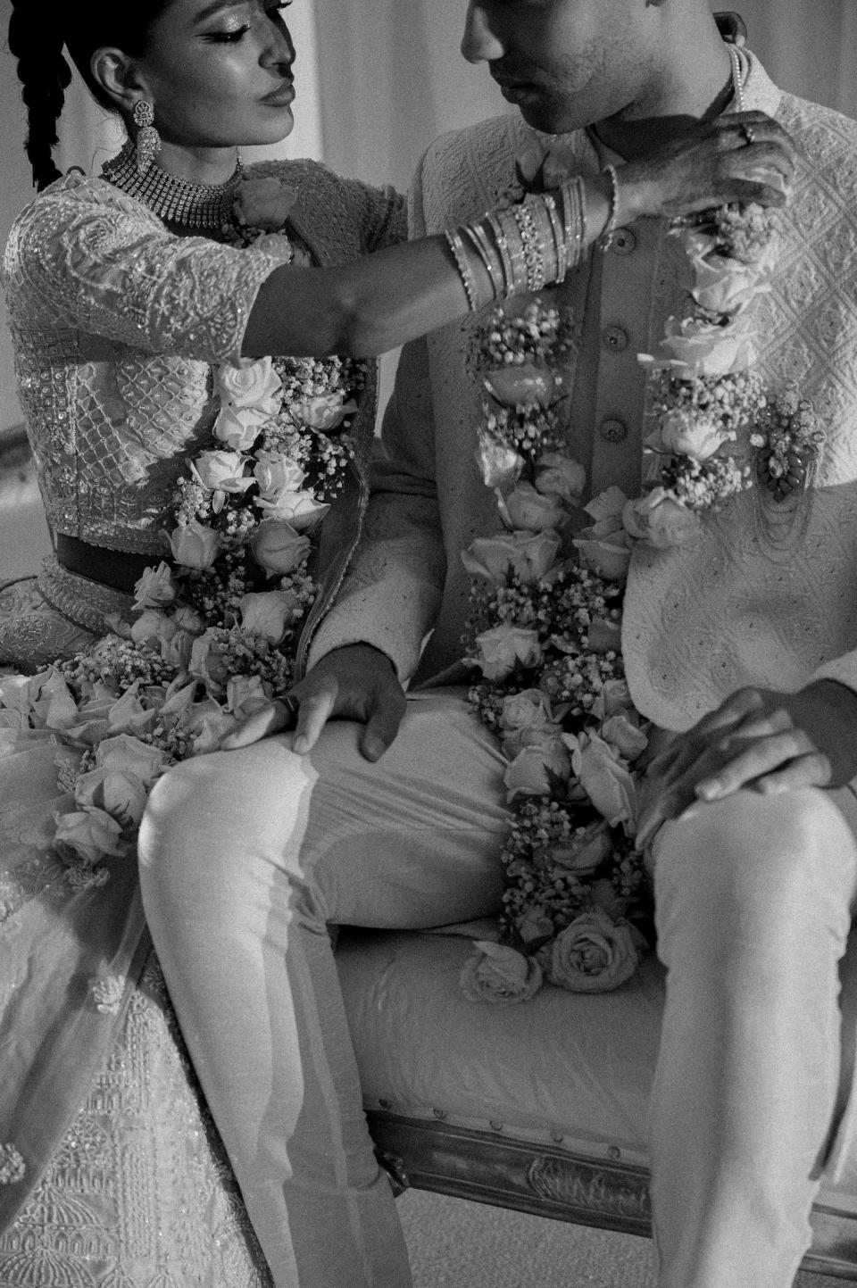 A bride adjusts her groom's mala on their wedding day.