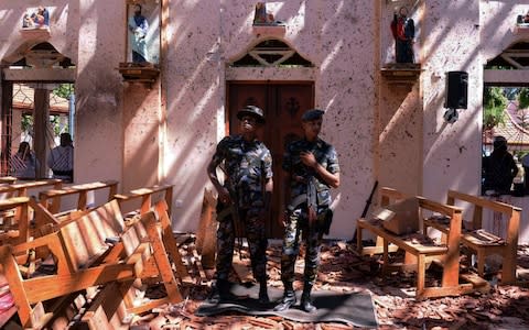 Sri Lankan military stand guard inside a church after an explosion in Negombo - Credit: &nbsp;STRINGER/REUTERS