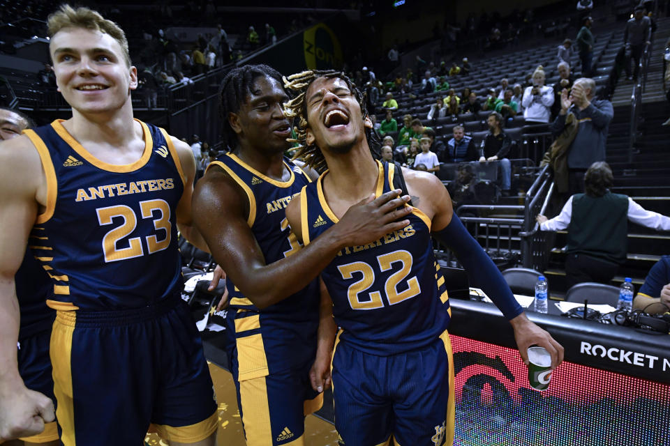 UC Irvine guard DJ Davis (22) celebrates with guard Emilis Butkus (23) and guard Ofure Ujadughele (10) after UC Irvine defeated No. 21 Oregon 69-56 in an NCAA college basketball game Friday, Nov. 11, 2022, in Eugene, Ore. (AP Photo/Andy Nelson)