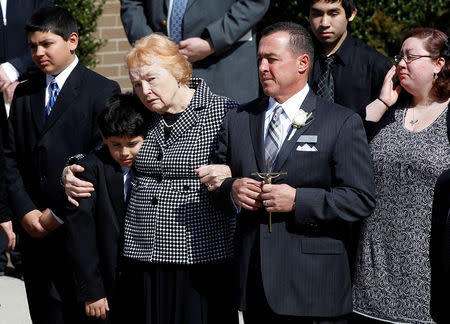 Rosemarie Colvin, the mother of journalist Marie Colvin, embraces a youth as her casket is carried out during the funeral service at St. Dominic’s Church in Oyster Bay, New York, March 12, 2012. REUTERS/Shannon Stapleton/File Photo