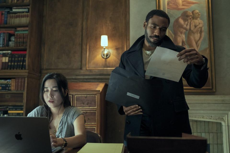 a man holding a paper and a woman sitting at a desk