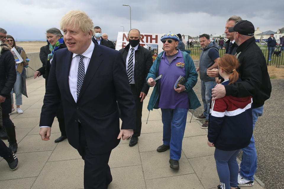 A member of the public, centre right, attempts to give Britain's Prime Minister Boris Johnson, foreground, a pro-EU leaflet as he campaigns on behalf of Conservative Party candidate Jill Mortimer, in Hartlepool, England, Monday, May 3, 2021, ahead of the 2021 Hartlepool by-election to be held on May 6. (Lindsey Parnaby/PA via AP)