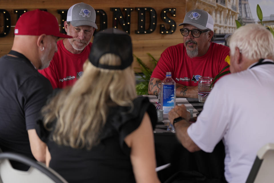 Greg McManik, second from left, and Bruno Panhoca, second from right, of the Pig Diamonds BBQ Team present their whole hog entry to judges at the World Championship Barbecue Cooking Contest, Saturday, May 18, 2024, in Memphis, Tenn. The team is comprised of members from Brazil and the United States. (AP Photo/George Walker IV)