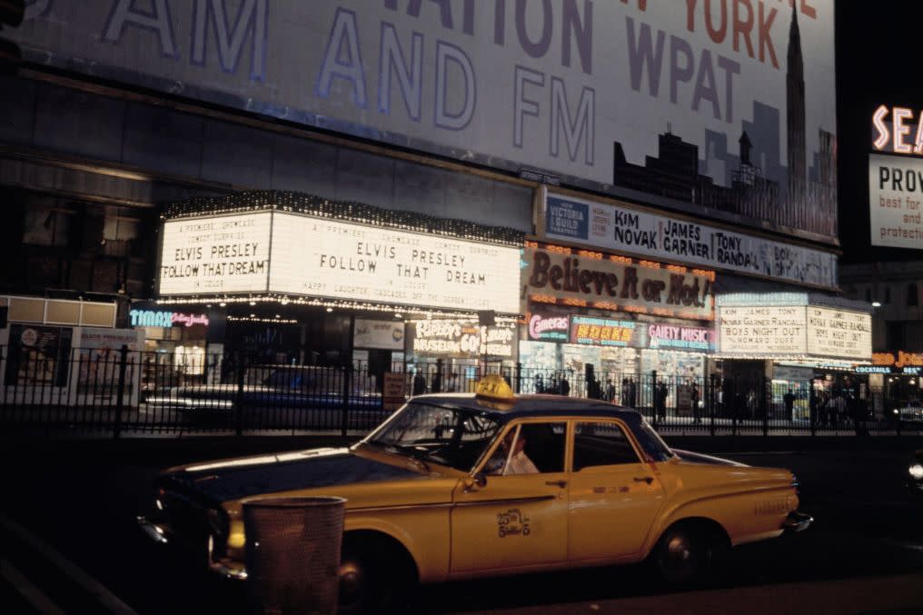 The Elvis Presley film 'Follow That Dream' is advertised at a cinema in Times Square, Manhattan, New York City, under a large hoarding for radio station WPAT, 1962.