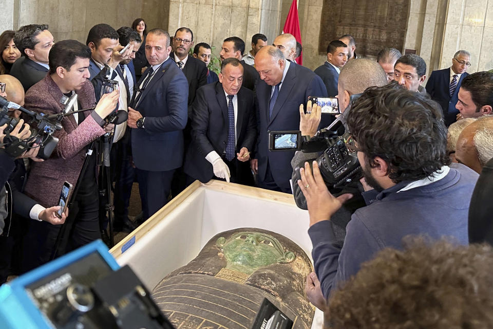 Foreign Minister Sameh Shoukry, center right, and Mostafa Waziri, top official at the Supreme Council of Antiquities, talk in front of an ancient wooden sarcophagus during a handover ceremony at the foreign ministry in Cairo, Egypt, Monday, Jan. 2, 2023. An ancient wooden sarcophagus that was featured at the Houston Museum of Natural Sciences was returned to Egypt after U.S. authorities determined it was looted years ago, Egyptian officials said Monday. (AP Photo/Mohamed Salah)