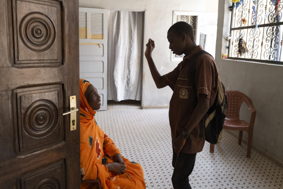 Mouhamed Sall, who is deaf, communicates by sign with his mother Khadiatou Koundio as he arrives home from school in Pikine, Senegal, Monday, March 18, 2024. Sall and three other students are part of a new approach in a small number of schools in Senegal that seat those who are deaf and hard of hearing with the rest of the class. (AP Photo/Sylvain Cherkaoui)