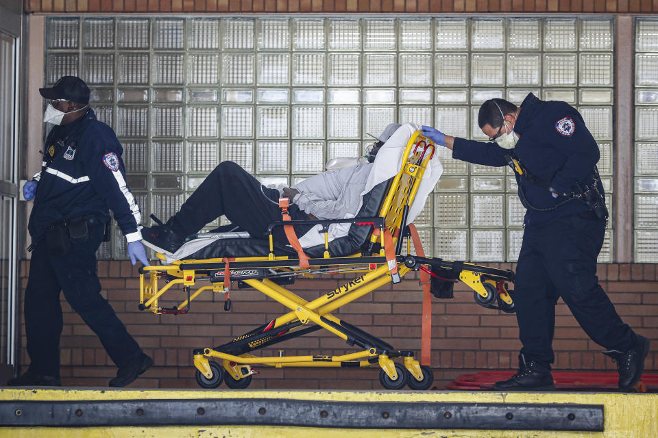 Paramedics wheel a patient wearing a breathing apparatus into the emergency room at Wyckoff Heights Medical Center, Monday, April 6, 2020, in New York. The new coronavirus causes mild or moderate symptoms for most people, but for some, especially older adults and people with existing health problems, it can cause more severe illness or death. (AP Photo/John Minchillo)