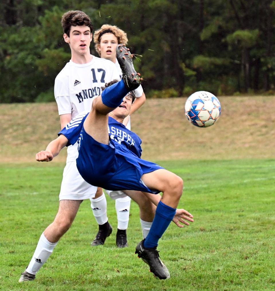 Thanos Pavlo of Mashpee flips back to kick the ball past Stephen Kelly of Monomoy.