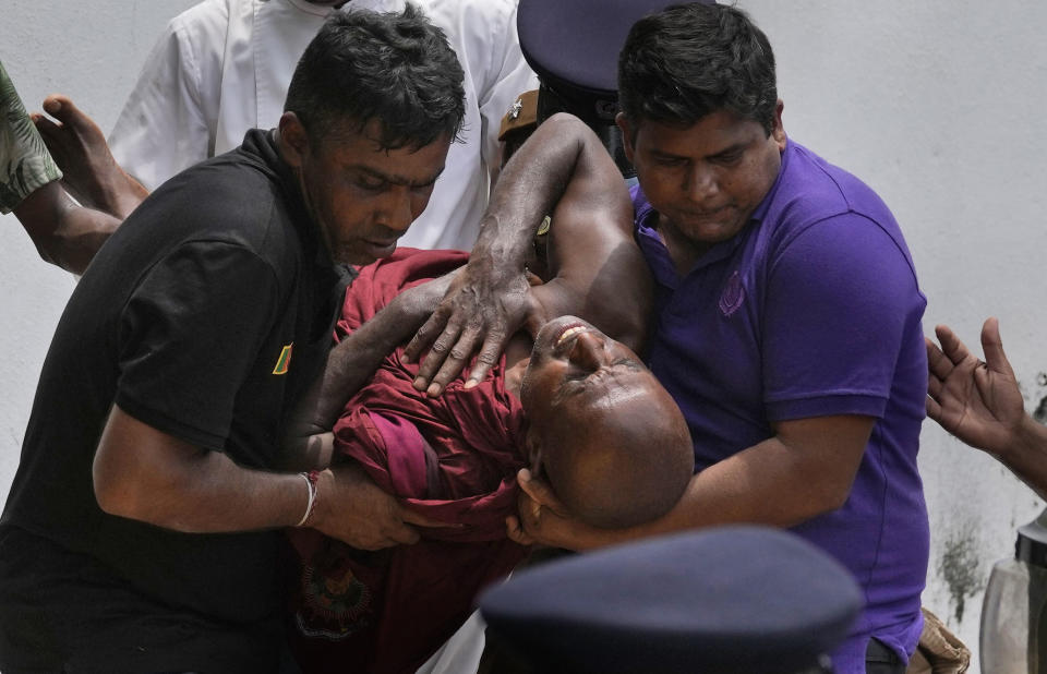 An injured Sri Lankan Buddhist monk is being carried away who among many other anti-government protesters were injured after attacked by government supporters outside prime minister Mahinda Rajapaksa's residence in Colombo, Sri Lanka, Monday, May 9, 2022. Government supporters on Monday attacked protesters who have been camped outside the offices of Sri Lanka's president and prime minster, as trade unions began a “Week of Protests” demanding the government change and its president to step down over the country’s worst economic crisis in memory. (AP Photo/Eranga Jayawardena)