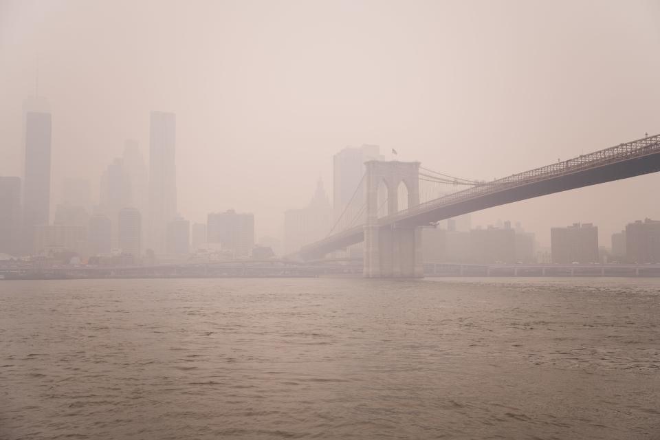 The Lower Manhattan skyline and Brooklyn Bridge are obscured by hazy skies on June 7, 2023, in New York City. Smoke and haze from large forest fires in Canada have covered the New York City region, blocking out sunlight and pushing the air quality index to hazardous levels.