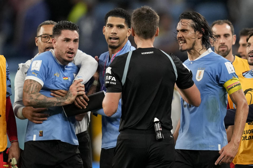 Uruguay's Edinson Cavani right argues with referee Daniel Siebert, of Germany, after hje booked him at the end of a World Cup group H soccer match against Ghana at the Al Janoub Stadium in Al Wakrah, Qatar, Friday, Dec. 2, 2022. (AP Photo/Darko Vojinovic)