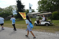 A local resident driving a golf cart wishes luck to farmworkers and allies as they march past, at the start of a five-day trek aimed at highlighting the Fair Food Program, which has enlisted food retailers to use their clout with growers to ensure better working conditions and wages for farmworkers, Tuesday, March 14, 2023, in Pahokee, Fla. (AP Photo/Rebecca Blackwell)