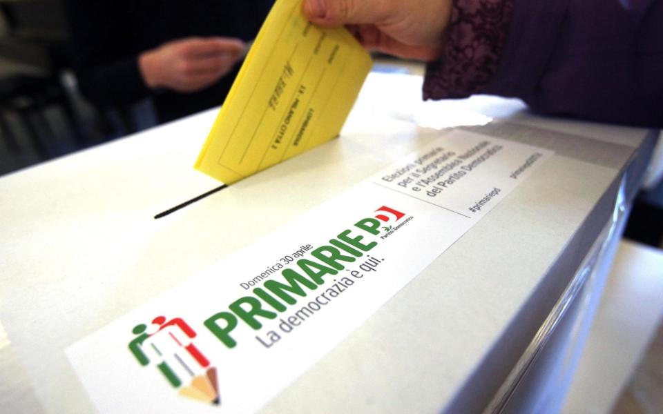 A woman casts her ballot for the Italian Democratic party's primary elections, in Milan - Credit: AP