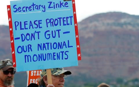 A man holds a sign as he waits at the Kanab Airport to protest U.S. Secretary of the Interior Ryan Zinke in Kanab, Utah - Credit: Getty