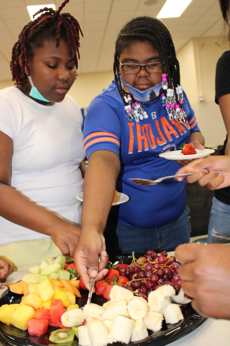 From left to right, Walnut Hill Elementary School students KeMarah S. and Jordan R. select fruit to eat after touring VSU Randolph Farm in Ettrick as part of Dominion Energy's Project Plant It! program on May 3, 2022.
