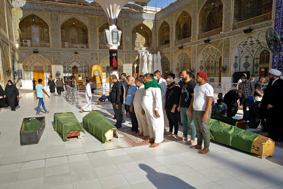 Mourners prepare to bury victims of a Monday bombing at a Baghdad market that was busy with shoppers a day before the Muslim Eid al-Adha holiday, in Najaf, Iraq, Tuesday, July 20, 2021. ​Iraqi medical officials said the Monday bomb attack in Sadr City, a Baghdad suburb, killed at least 30 people and wounded dozens of others. (AP Photo/Anmar Khalil)