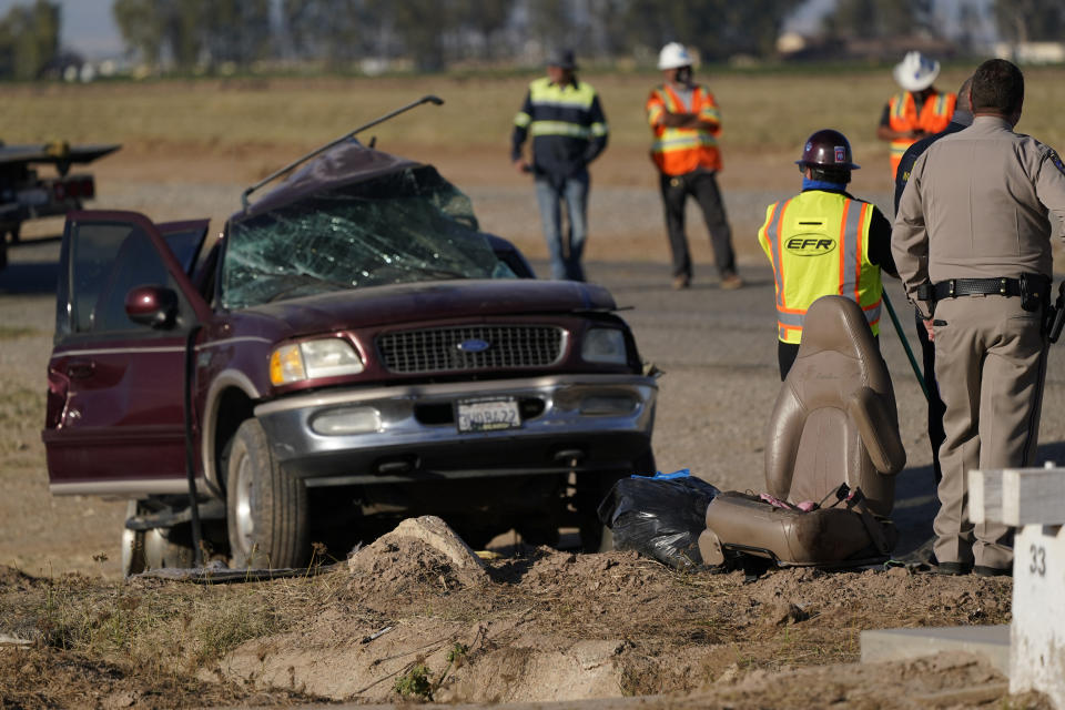 FILE - In this March 2, 2021 file photo law enforcement officers sort evidence and debris at the scene of a deadly crash in Holtville, Calif. A Mexican man has been charged with coordinating a smuggling effort that left 13 people dead when their overloaded SUV was struck by a big-rig just over the border in California. The U.S. attorney's office says Jose Cruz Noguez of Mexicali appeared in federal court in El Centro on Tuesday, March 30, 2021, but didn't enter a plea to smuggling and conspiracy charges. (AP Photo/Gregory Bull, File)