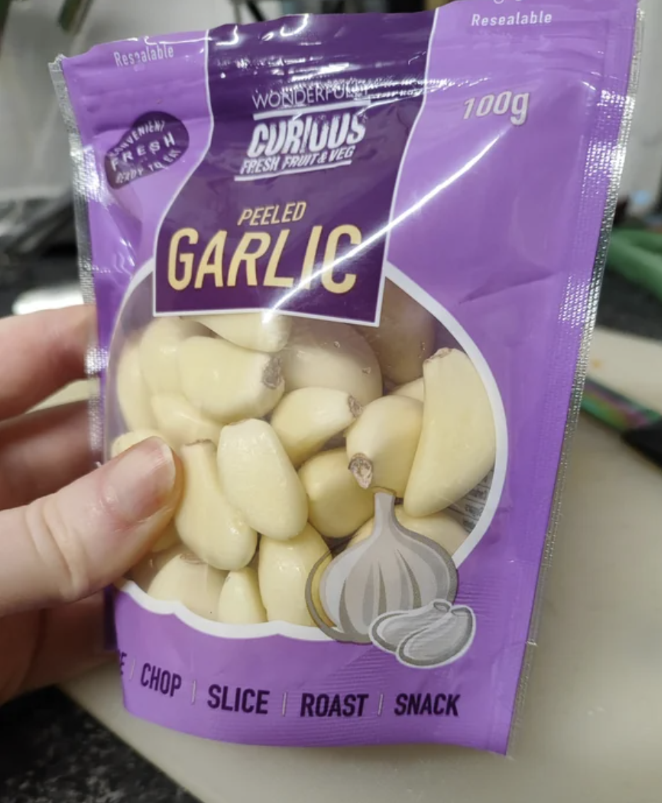A person is showing off a bag of peeled garlic and suggesting it could be a snack