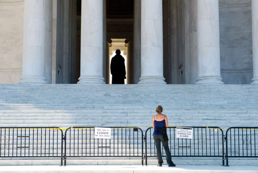 A woman views the Jefferson Memorial from behind barricades in Washington.