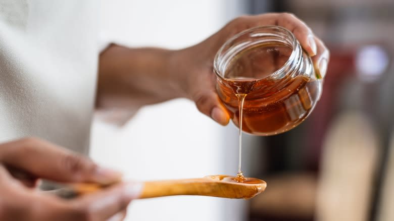 Woman pouring honey onto spoon