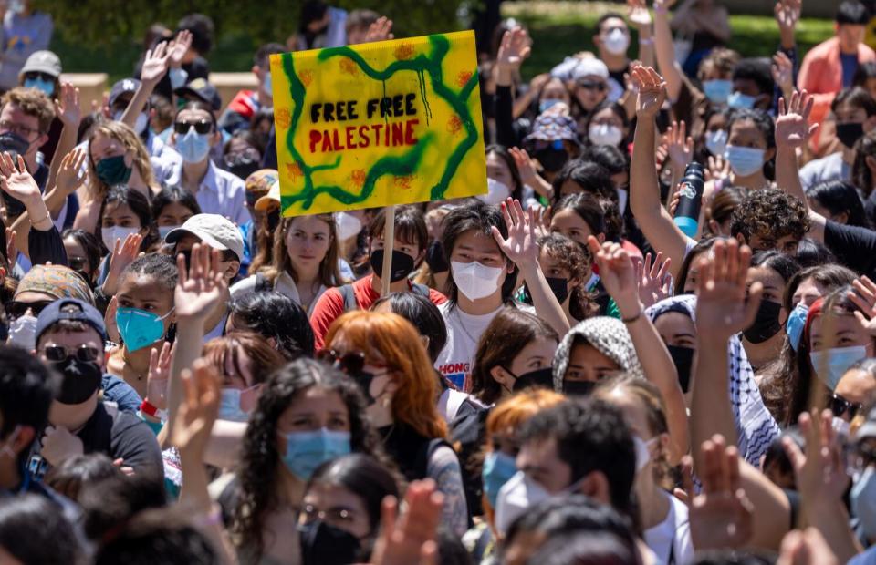 A crowd of protesters holds a sign reading "Free Free Palestine"