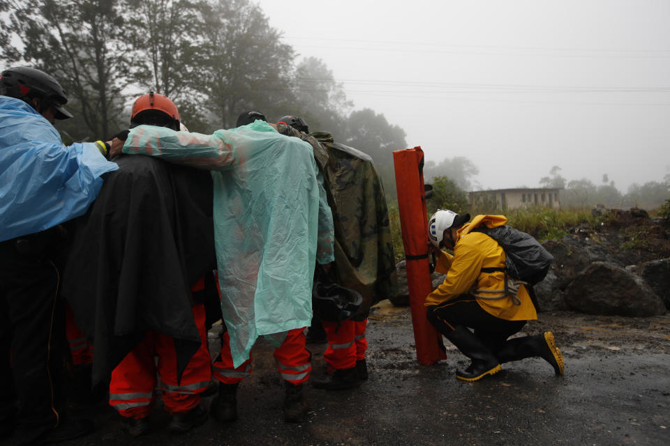 Volunteer firefighters huddle in prayer before beginning a search and rescue operation in San Cristobal Verapaz, Saturday, Nov. 7, 2020, in the aftermath of Hurricane Eta. Searchers in Guatemala were digging through mud and debris looking for an estimated 100 people believed buried by a massive, rain-fueled landslide, as Eta regained tropical storm strength and churned toward Cuba. (AP Photo/Moises Castillo)