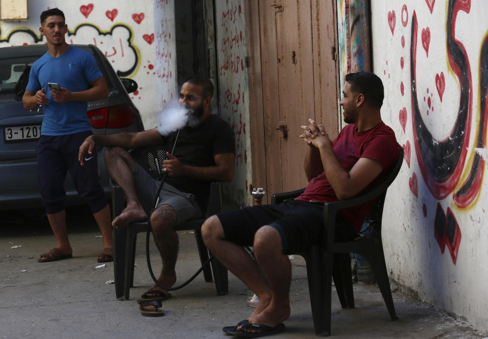 A man smokes a water pipe on a street during a lockdown imposed during the coronavirus pandemic, at Shati refugee camp, in Gaza City, Thursday, Aug. 27, 2020. On Wednesday Gaza's Hamas rulers extended a full lockdown in the Palestinian enclave for three more days as coronavirus cases climbed after the detection this week of the first community transmissions of the virus in the densely populated, blockaded territory. (AP Photo/Adel Hana)