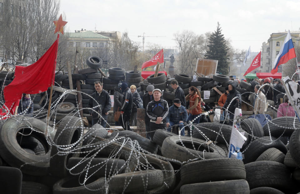People stand at a barricade at the regional administration building that they had seized earlier in Donetsk, Ukraine, Tuesday, April 15, 2014. Several government buildings have fallen to mobs of Moscow loyalists in recent days as unrest spreads across the east of the country. (AP Photo/Efrem Lukatsky)