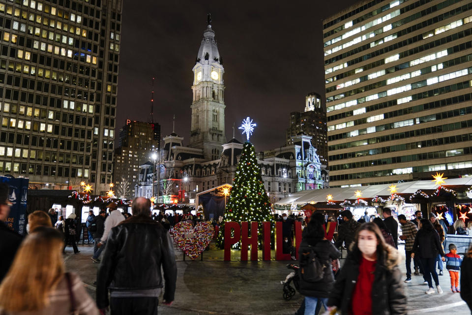 FILE - People including some wearing face masks to protect against the spread of the coronavirus visit the Christmas Village in Philadelphia, Wednesday, Dec. 15, 2021. The delta and omicron variants of the coronavirus are trying to spoil the holiday spirit, but there are ways to reduce risk while enjoying the festivities. The explosive spread of the omicron variant is causing many to wonder if they should cancel their holiday plans. (AP Photo/Matt Rourke)