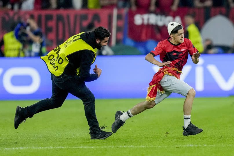 Ein Sicherheitsmitarbeiter jagt einen Eindringling während des Spiels der Gruppe B zwischen Albanien und Spanien  am Montag, 24. Juni 2024..