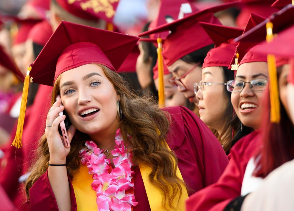 Haley Walters uses her cell phone to locate her mother in the spectator seating area at the Pasadena City College graduation ceremony, June 14, 2019, in Pasadena, California. Walters is five years shy of earning a law degree and, if everything goes according to plan, she should be indebted for $100,000 by the time she enters the workforce. (Photo by Robyn Beck / AFP) 