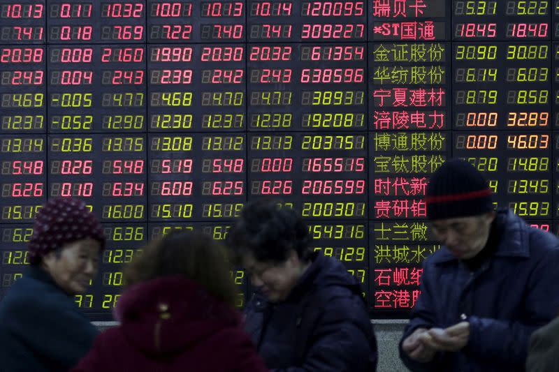 FILE PHOTO: FILE PHOTO: Investors stand in front of an electronic board showing stock information on the first trading day after the week-long Lunar New Year holiday at a brokerage house in Shanghai