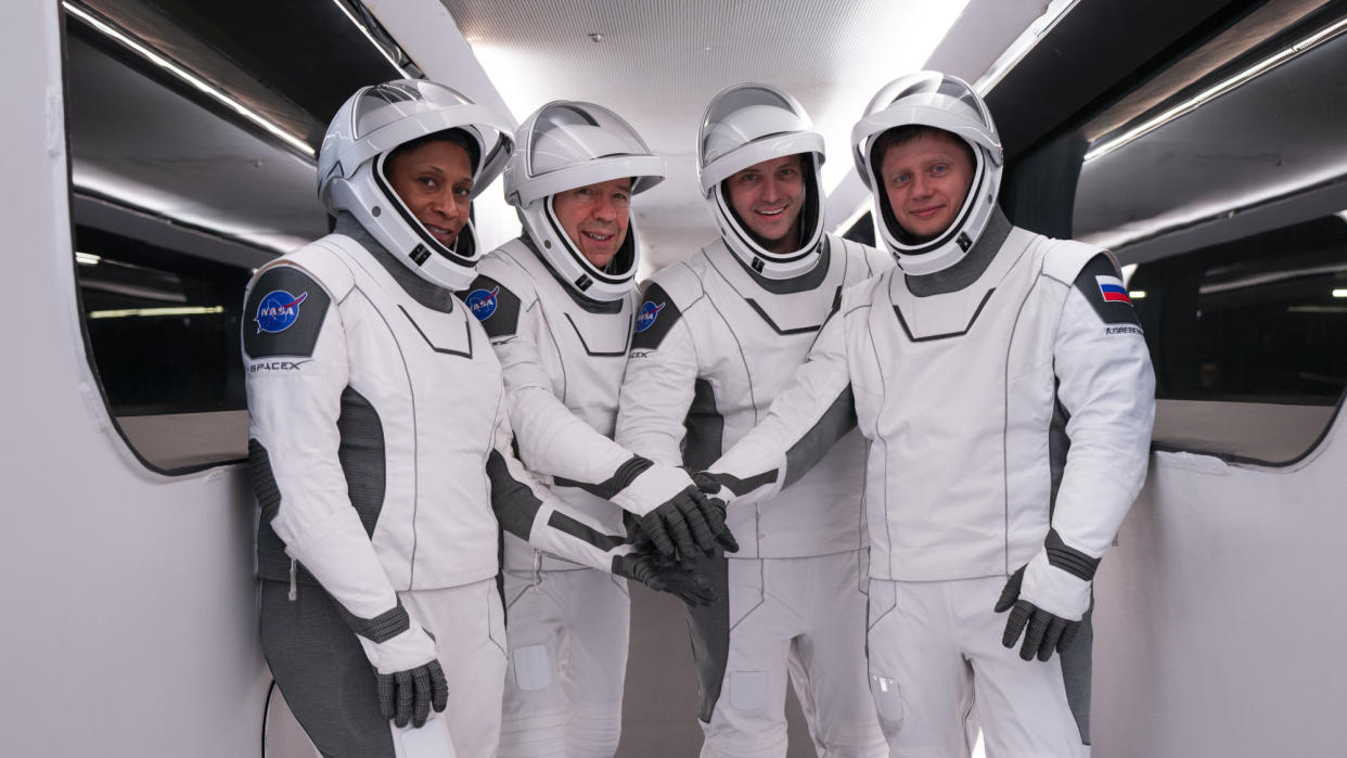  Four Crew-8 astronauts in white SpaceX spacesuits with their arms together for ahead of launch. 