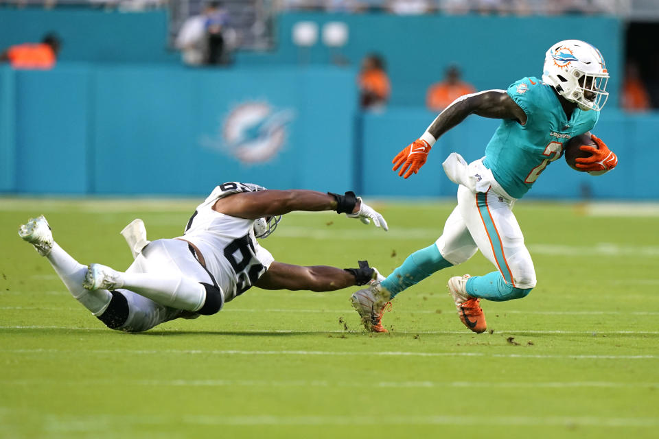 Miami Dolphins running back Chase Edmonds (2) avoids a tackle by Las Vegas Raiders defensive end Myron Tagovailoa-Amosa (69) during the first half of a NFL preseason football game, Saturday, Aug. 20, 2022, in Miami Gardens, Fla. (AP Photo/Lynne Sladky)