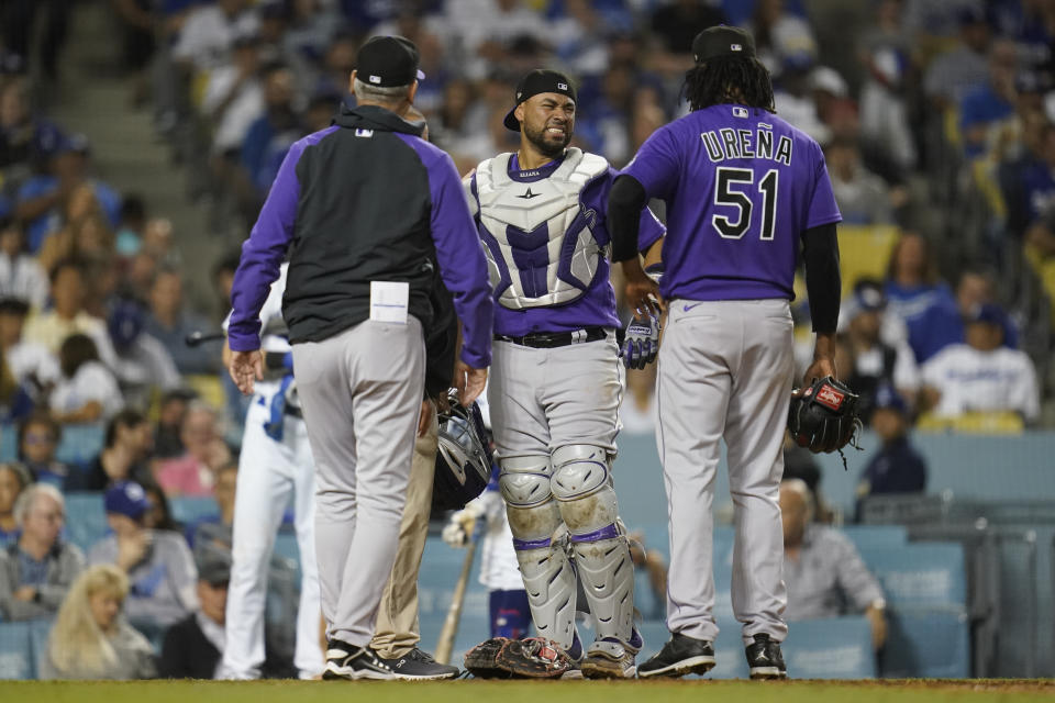 Colorado Rockies catcher Elias Diaz, center, is checked out after he was hit by a pitch during the fifth inning of a baseball game against the Los Angeles Dodgers in Los Angeles, Monday, Oct. 3, 2022. (AP Photo/Ashley Landis)