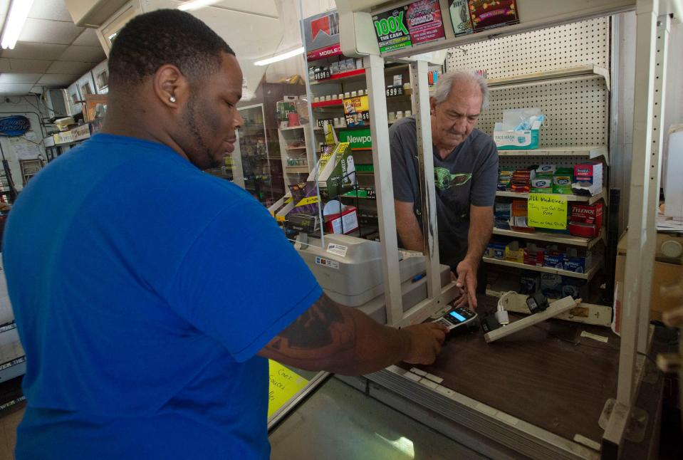 Sonny Holmes helps customer Alec Riley with his final purchases at the Yellow Store on Friday. The longtime Pensacola convenience store is closing after 32 years.