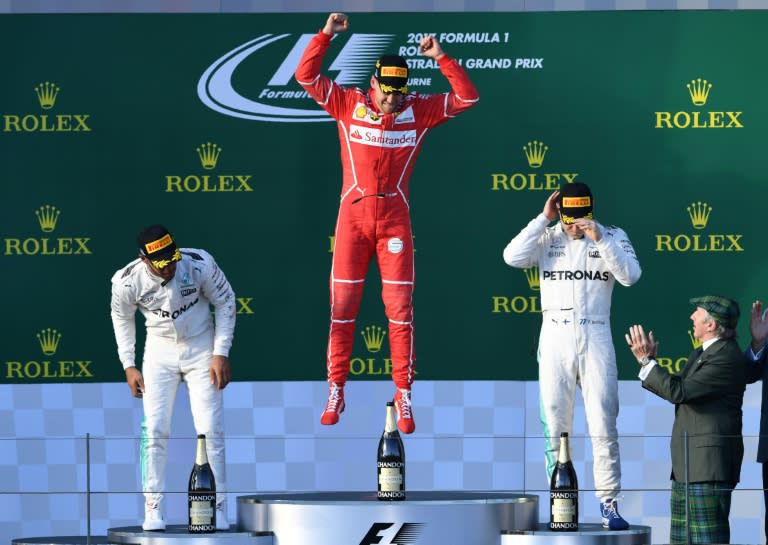 Ferrari's Sebastian Vettel (C) celebrates on the podium beside second-placed Mercedes' Lewis Hamilton (L) and third-placed Mercedes' Valtteri Bottas at the Australian Grand Prix in Melbourne