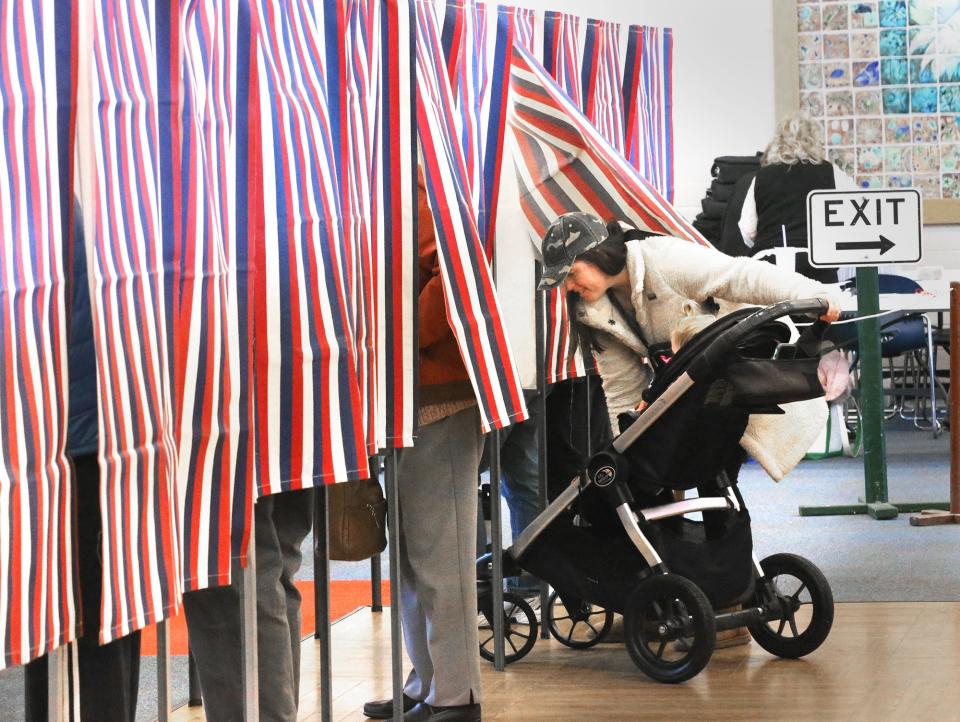 Hampton voter Colleen Poisson and her daughter Ellie negotiate booth space for the stroller at the polls on March 12, 2024.